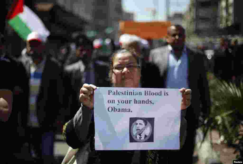 A Palestinian woman holds a sign during a protest against the visit of U.S. President Barack Obama, in Gaza City, March 20, 2013. 