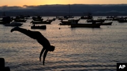 Un hombre se lanza desde un muelle al atardecer en Tongoy, Chile, el martes 21 de enero de 2025. 