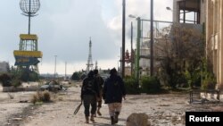 Rebel fighters walk around al-Hamidiyeh base, one of two military posts they took control of from forces loyal to Syria's President Bashar al-Assad in the northwestern province of Idlib, Dec. 15, 2014. 