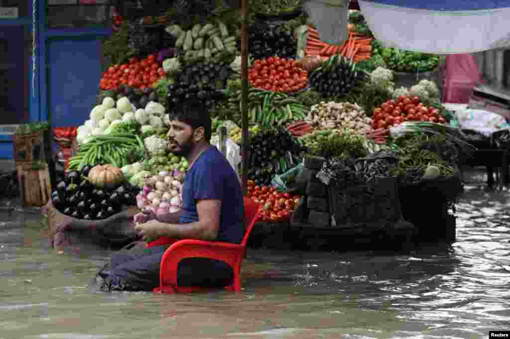 لاہور کا ایک سبزی فروش بارش کے پانی سے گھرا ہونے کے باوجود گاہکوں کے انتظار میں ہے &nbsp; &nbsp; 