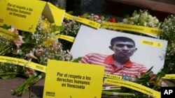 FILE - Photo of a Venezuela citizen is seen in front of Venezuela's embassy building during a protest by the human rights organization Amnesty International in Lima, Peru, April 12, 2018. The signs on the ground read in Spanish "Respcet human rights in Venezuela."