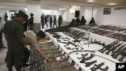 Soldiers review a weapons cache that includes 154 rifles and shotguns and over 92,000 rounds of ammunition during a media presentation, in Mexico City, Mexico, June 3, 2011