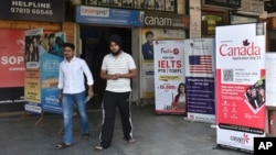 FILE - People walk past banners inviting students to study in Canada and other places abroad at a market in Amritsar, in the northern Indian state of Punjab, Oct. 15, 2024.