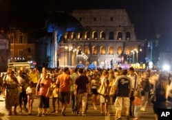 FILE - People gather at the Fori Imperiali avenue, with the Colosseum in the background, during an event celebrating the ban on private vehicles, in Rome, Aug. 3, 2013.