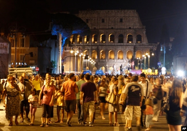 FILE - People gather at the Fori Imperiali avenue, with the Colosseum in the background, during an event celebrating the ban on private vehicles, in Rome, Aug. 3, 2013.