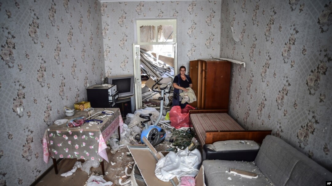 A woman stands inside her damaged house two days after shelling by Armenian's artillery during fighting over the separatist region of Nagorno-Karabakh, in Ganja, Azerbaijan, Oct. 13, 2020. 