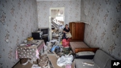 A woman stands inside her damaged house two days after shelling by Armenian's artillery during fighting over the separatist region of Nagorno-Karabakh, in Ganja, Azerbaijan, Oct. 13, 2020. 