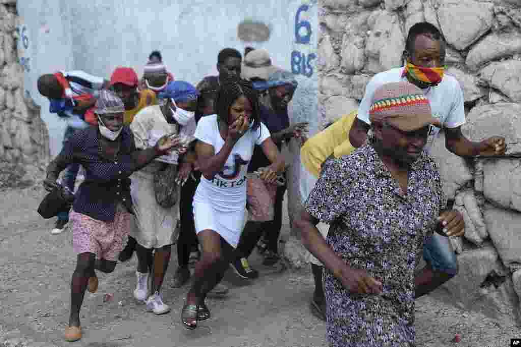 People who were marching to the prime ministers&#39; residence, to demand justice for the assassination of Haitian President Jovenel Moise, run from tear gas fired by police in Port-au-Prince, Haiti.