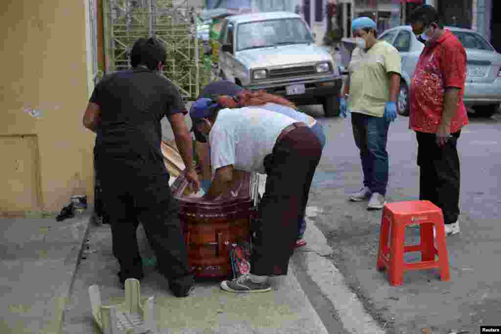 Miembros de una familia ponen el cadáver de una mujer dentro de un ataúd, el 30 de marzo de 2020, después de que esta muriera en su casa por la COVD-19.&nbsp;