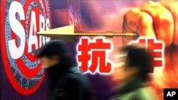 資料照： 上海市民走過街頭張貼的抗沙士（非典）政府宣傳畫。 （2003年12月18日）