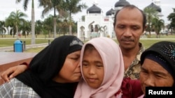 Jamaliah (L) kisses her daughter Raudhatul Jannah, 14, as the girl's father Septi Rangkuti and grandmother Sarwani look on following prayers at Baiturrahman mosque in Banda Aceh, Aug. 8, 2014. 