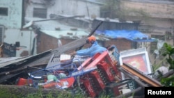 Cư dân thu nhặt các vật dụng còn sót lại từ đóng đổ nát của nhà cửa sau trận bão Nari tại Đà Nẵng.