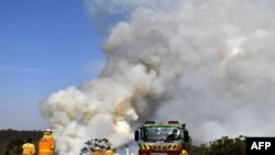 Firefighters work as smoke rises from a bushfire in Penrose, New South Wales, Australia, Jan. 10, 2020. High temperatures and strong winds were expected to fan massive bushfires blazing across southeastern Australia after several days of reprieve.