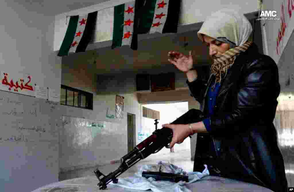 This image provided by Aleppo Media Center AMC shows the mother of a Syrian rebel cleaning a rifle, in Aleppo, May 14, 2013.