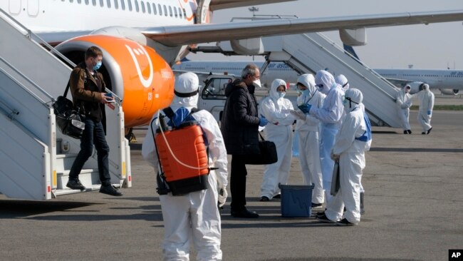 资料照：哈萨克斯坦医护人员在阿拉木图机场检查乘客是否感染新冠病毒。（2020年3月27日）