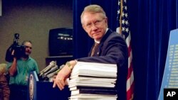 FILE - Sen. Harry Reid, D-Nev., leans on a stack of documents pertaining to campaign finance reform during a Capitol Hill news conference on Dec. 3, 1996
