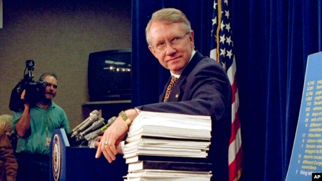 FILE - Sen. Harry Reid, D-Nev., leans on a stack of documents pertaining to campaign finance reform during a Capitol Hill news conference on Dec. 3, 1996