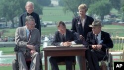 President George Bush signs the Americans with Disabilities Act during a ceremony on the South Lawn of the White House July 26, 1990. 