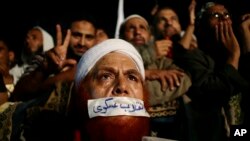 Seorang pendukung presiden Mesir terguling Mohamed Morsi menutup mulutnya dengan plester bertuliskan huruf Arab yang berbunyi "Kudeta Militer" di Nasr City, Kairo.