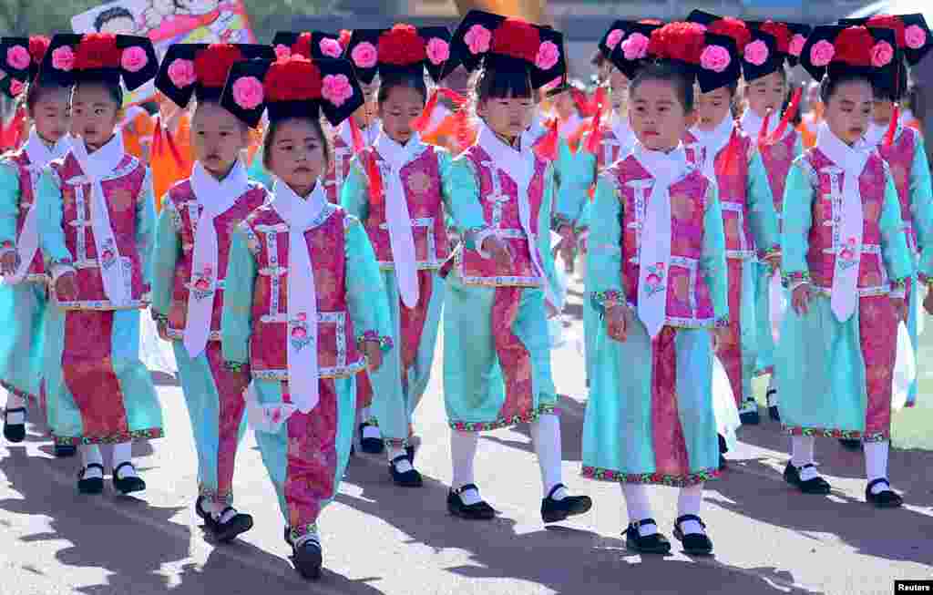 Primary school students wearing traditional Chinese costumes walk during a sports event in Shenyang, Liaoning province, China.