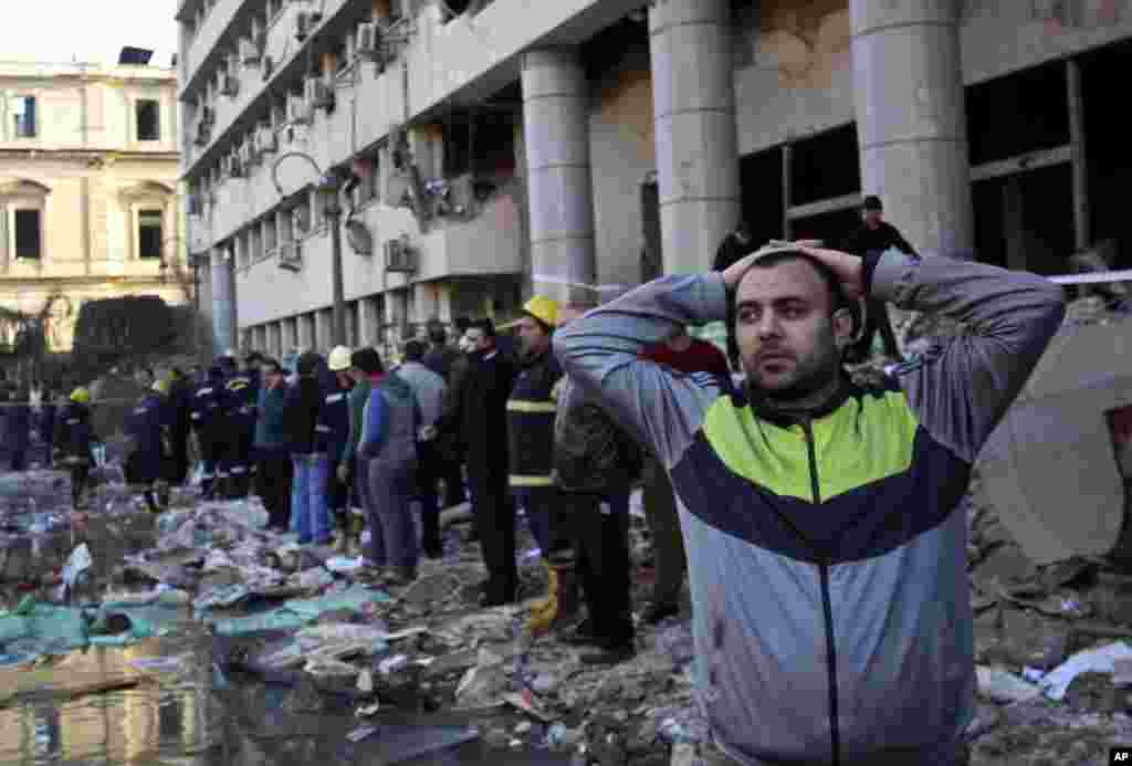 A man stands in rubble after an explosion at the Egyptian police headquarters in downtown Cairo. Three bombings hit high-profile areas around the city on Friday, including a suicide car bomber who struck the police headquarters. 