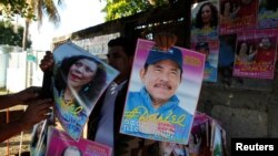 A man holds campaign posters in support of Nicaragua's President Daniel Ortega and vice presidential candidate first lady Rosario Murillo in Managua, Oct. 27, 2016.