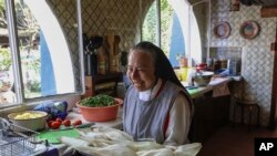 FILE - Nun Maria Ines Maldonado, 76, carries a tray of corn husks stuffed with shredded chicken and salsa verde at the Convent of the Mothers Perpetual Adorers of the Blessed Sacrament in Mexico City, December 1, 2023.