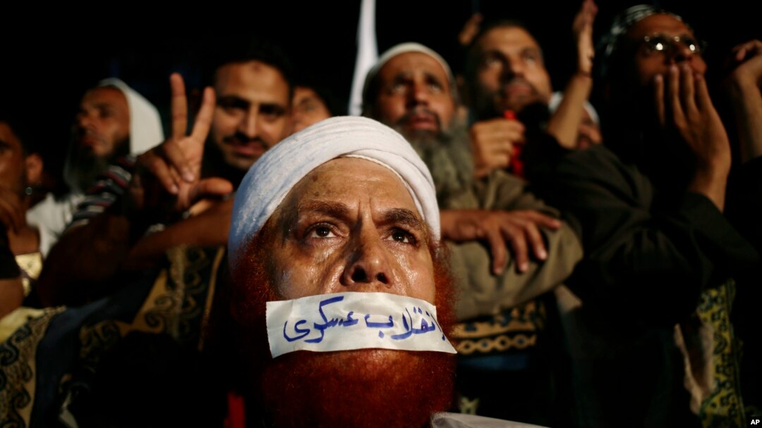 Seorang pendukung presiden Mesir terguling Mohamed Morsi menutup mulutnya dengan plester bertuliskan huruf Arab yang berbunyi "Kudeta Militer" di Nasr City, Kairo.