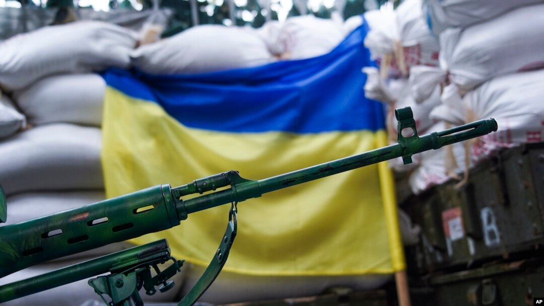 FILE - A rifle is seen in front of a Ukrainian flag in the village of Mariinka, near Donetsk, eastern Ukraine, Aug. 25, 2016.