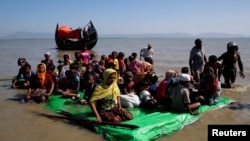 Rohingya refugees sit on a makeshift boat as they await permission from Border Guard Bangladesh to continue after crossing the Bangladesh-Myanmar border, at Shah Porir Dwip near Cox's Bazar, Bangladesh, Nov. 9, 2017. 