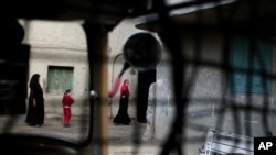 In this Nov. 5, 2014 photo, relatives of 13-year-old Soheir al-Batea who died undergoing the procedure of female genital mutilation walk in front of her home in Dierb Biqtaris village, some 120 kilometers (75 miles) northeast of Cairo, Egypt.