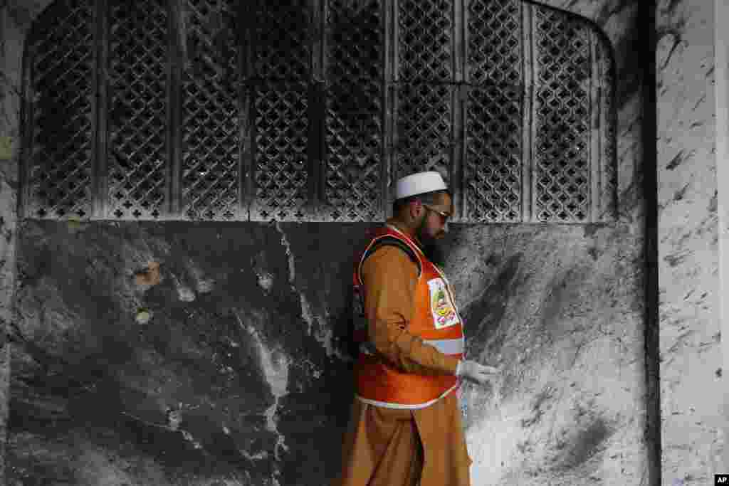 A Pakistani official collects forensic evidence at a Shi&#39;ite mosque attacked by suicide bombers and gunmen in Peshawar, Feb. 13, 2015.