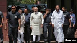 India's Prime Minister Narendra Modi (C) walks to speak with the media as he arrives to attend his first Parliament session in New Delhi, June 4, 2014. 