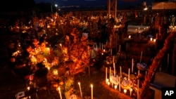 Familiares pasan la noche junto a la tumba de sus seres queridos durante las festividades del Día de Muertos en el cementerio Arocutin en el estado de Michoacán, México, el lunes 1 de noviembre de 2021. 