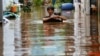 Seorang pria membawa barang-barangnya mengarungi genangan air yang merendam jalan menyusul hujan lebat di Jakarta, Sabtu, 20 Februari 2021. (Foto: Ajeng Dinar Ulfiana/Reuters)