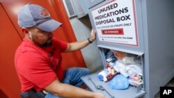 In this Sept. 11, 2019, photo, narcotics detective Paul Laurella retrieves unused medications from the police department's disposal box in Barberton, Ohio. Jury selection is set to begin Wednesday, Oct. 16, 2019.