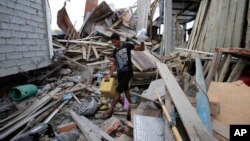 A man whose pregnant wife was killed during an earthquake Saturday, gathers things from his collapsed home, in La Chorrera, Ecuador, April 18, 2016.