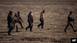 FILE - Syrian Democratic Forces fighters escort suspected Islamic State militants in Hasakeh, northeast Syria, Jan. 26, 2022. SDF forces said Jan. 6, 2023, that they had arrested more than 100 suspects in an eight-day operation against IS militants. 