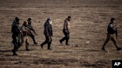 FILE - Syrian Democratic Forces fighters escort suspected Islamic State militants in Hasakeh, northeast Syria, Jan. 26, 2022. SDF forces said Jan. 6, 2023, that they had arrested more than 100 suspects in an eight-day operation against IS militants. 