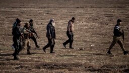 FILE - Syrian Democratic Forces fighters escort suspected Islamic State militants in Hasakeh, northeast Syria, Jan. 26, 2022. SDF forces said Jan. 6, 2023, that they had arrested more than 100 suspects in an eight-day operation against IS militants. 