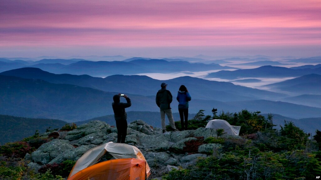 Robert Weiss of Tewksbury, Mass., left, photographs his brother-in-law, Matthew Ferri, of Dracut, Mass., and his wife, Andrea Weiss just before sunrise from their campsite on the Appalachian Trail in Beans Purchase, N.H., Sunday, Sept. 17, 2017. (AP Photo/Robert F. Bukaty)