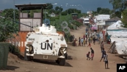 Some of the more than 30,000 Nuer civilians sheltering in a U.N. base in South Sudan's capital, Juba, for fear of targeted killings by government forces walk by an armored vehicle and a watchtower manned by Chinese peacekeepers, July 25, 2016.