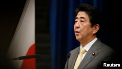 FILE - Japan's Prime Minister Shinzo Abe speaks next to the Japanese national flag.