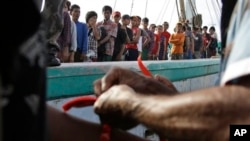 Petugas di Indonesia memberi pita di pergelangan tangan nelayan Burma yang telah diselamatkan sebagai identifikasi saat tiba di Tual (4/4). (AP/Dita Alangkara)