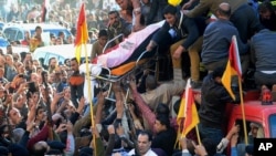 Egyptians carry the coffin of a victim killed from an explosion at a police headquarters, during the funeral procession of a dozen policeman and a civilian killed, in the Nile Delta city of Mansoura, north of Cairo, Egypt, Dec. 24, 2013.