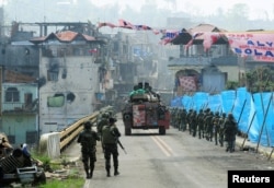 An armored personnel carrier and government troops march toward Mapandi bridge after 100 days of intense fighting between soldiers and insurgents from the Maute group, who have taken over parts of Marawi city, southern Philippines, Aug. 30, 2017.