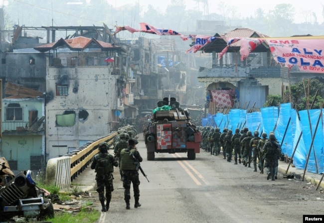 An armored personnel carrier and government troops march toward Mapandi bridge after 100 days of intense fighting between soldiers and insurgents from the Maute group, who have taken over parts of Marawi city, southern Philippines, Aug. 30, 2017.