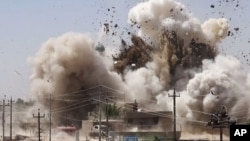 In this undated photo posted on a militant website that frequently carries official statements from the Islamic State extremist group, smoke and debris go up in the air as Shiite's Al-Qubba Husseiniya mosque explodes in Mosul. 