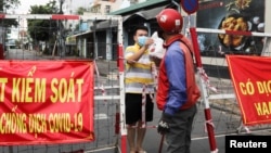 FILE - A man living in an area under lockdown receives food through a barricade during the coronavirus disease (COVID-19) pandemic in Ho Chi Minh City, Vietnam July 20, 2021. (REUTERS/Stringer/File Photo)