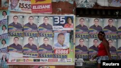 FILE - A woman walks past election posters in Sao Luis, Brazil, Oct. 2, 2016. 